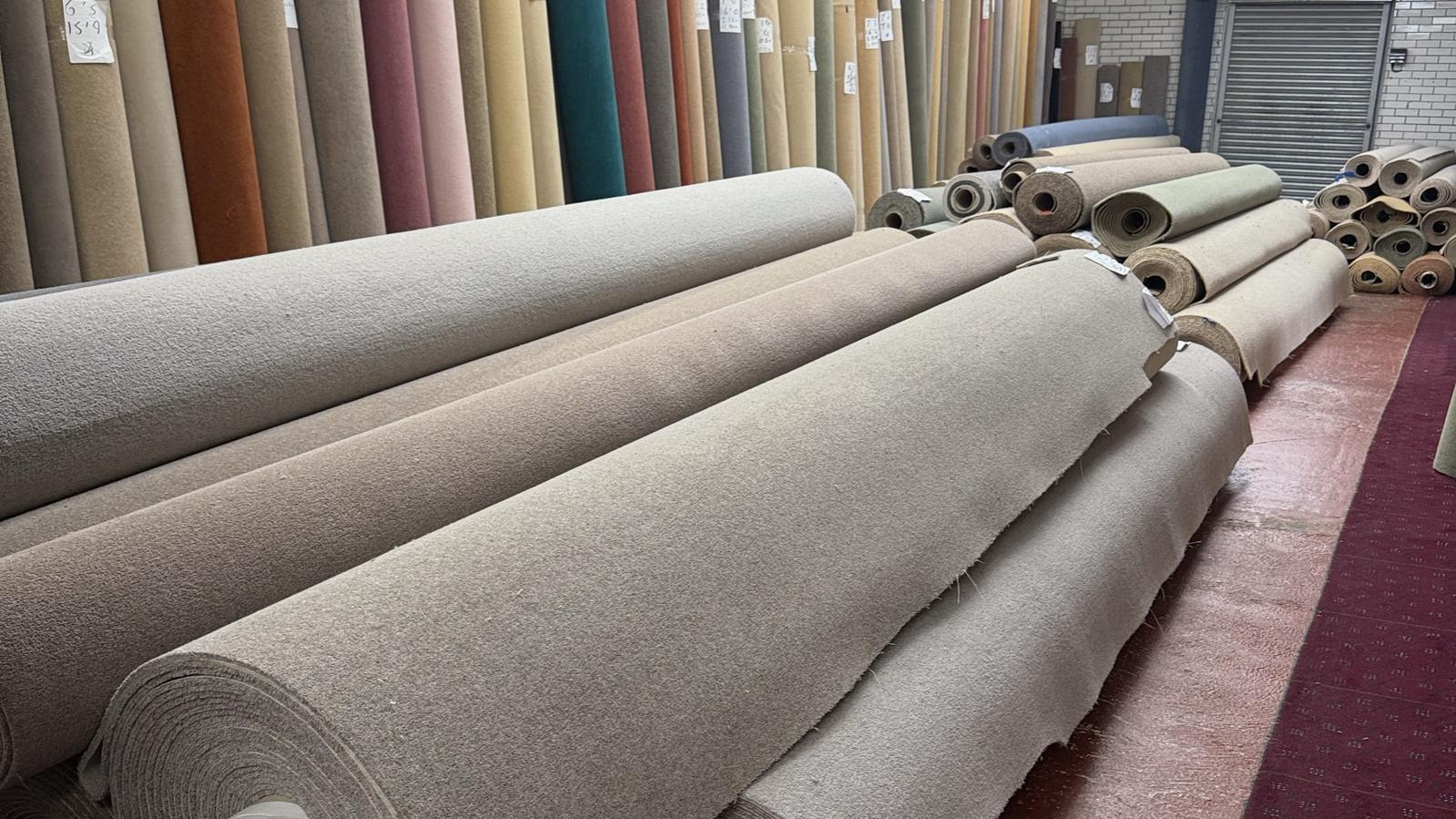 Rows of carpet rolls and remnants in the Howkel showroom, each marked with its size