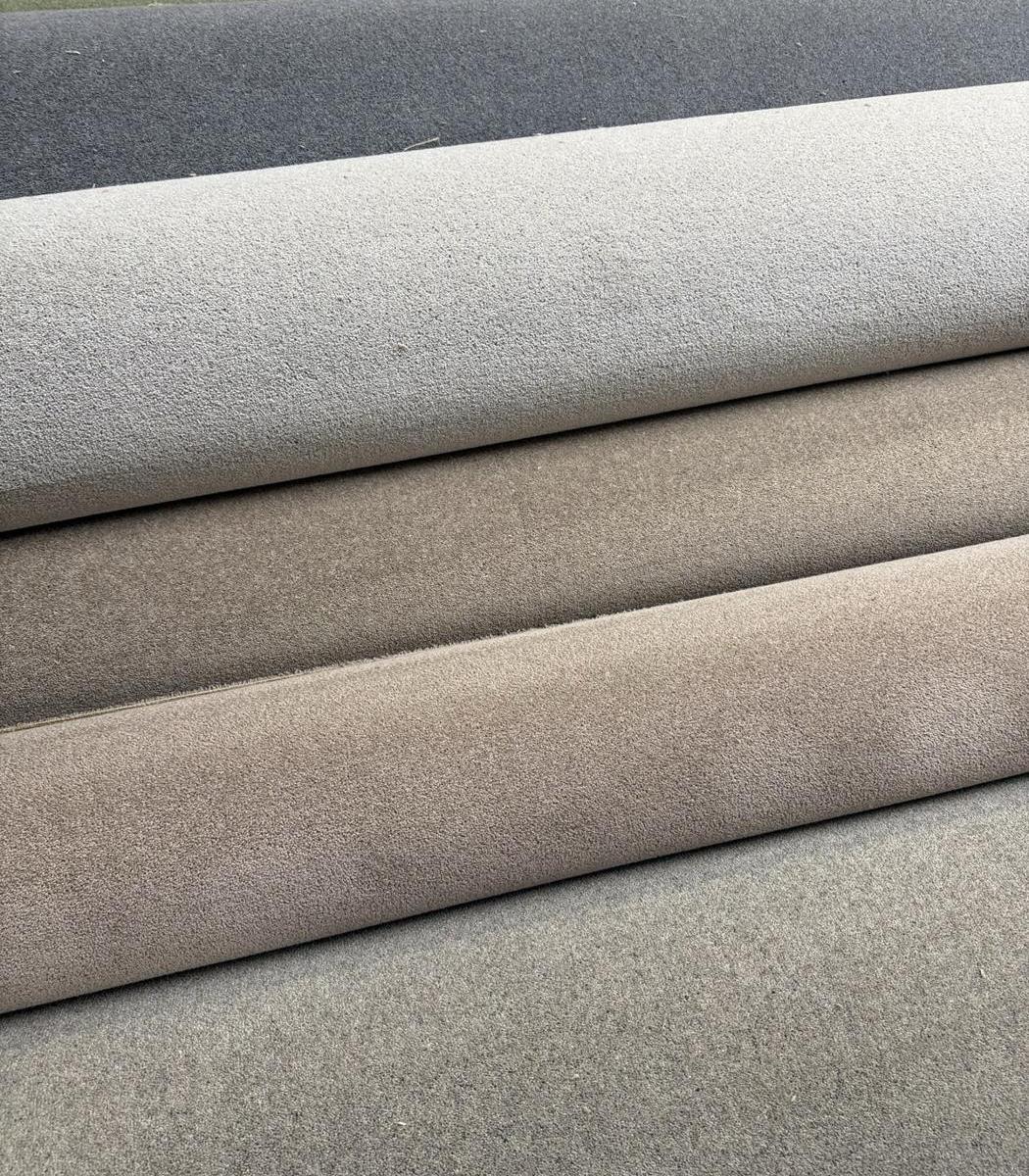 Rolls of grey, stone and taupe carpet laid side by side